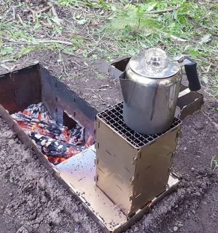 A StealthFyre stove set into a dug fire pit with a percolator heating on the panel top